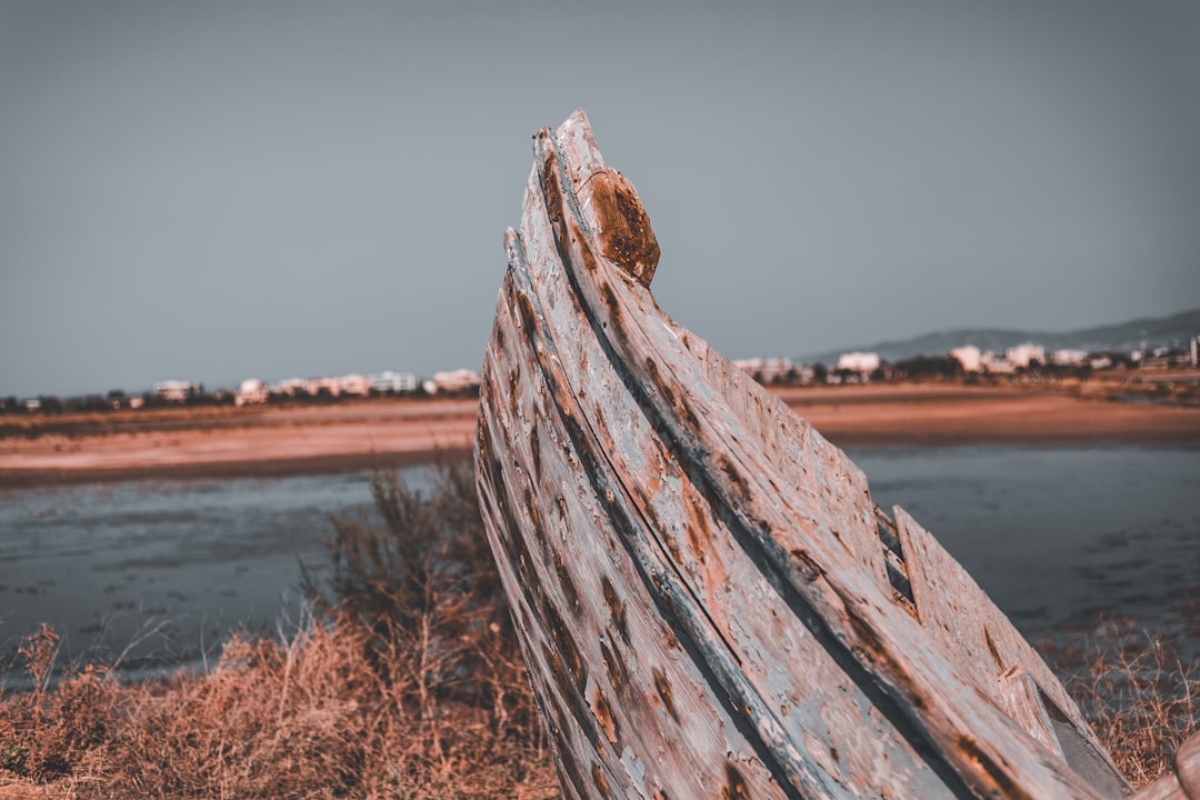an old boat sitting on top of a dry grass field