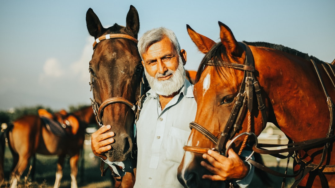 a man standing next to two horses in a field